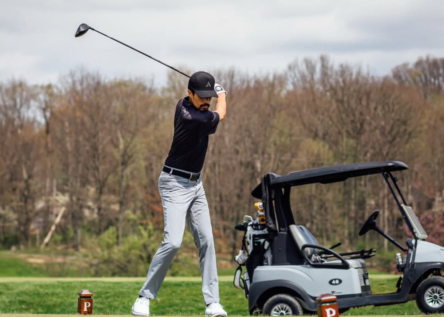Person playing golf on a course with a golf cart in the background