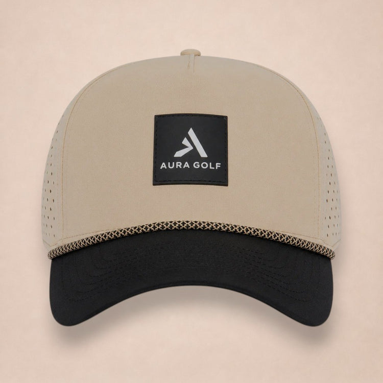 Apex hat, front view, tan crown with black brim, tan-and-black braided rope and a square black Aura Golf patch.