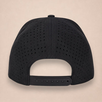Noir hat, back view, black perforated panels and a black adjustable snapback strap, on a plain beige background.